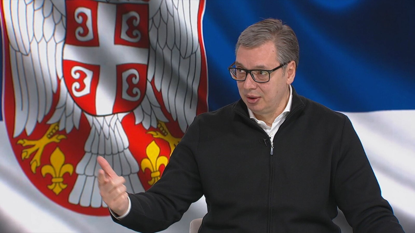 Президент Сербии Александар Вучич на фоне государственного флага во время выступления о закупке ракет