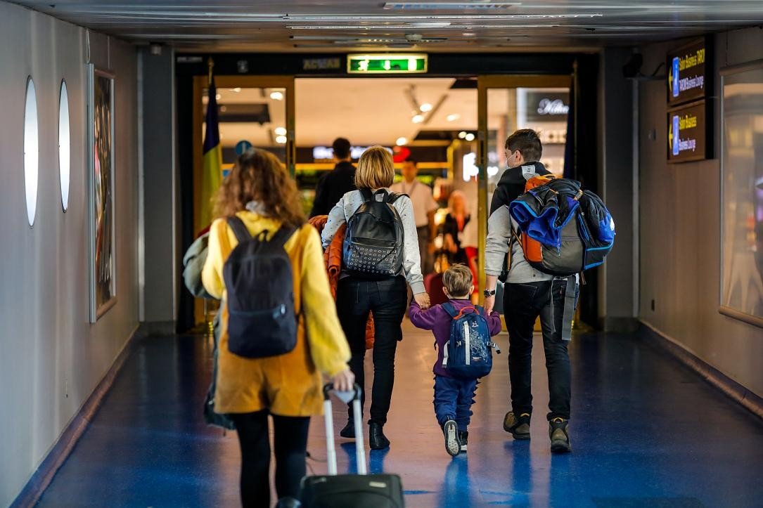 Семья с ребёнком идёт по коридору аэропорта — типичная сцена эмиграции из Румынии