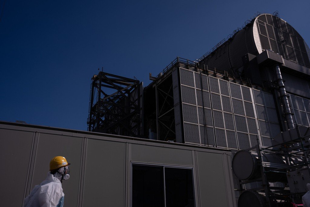 Рабочий в защитном костюме и респираторе у здания ядерного реактора — тема безопасности остаётся ключевой в дискуссии