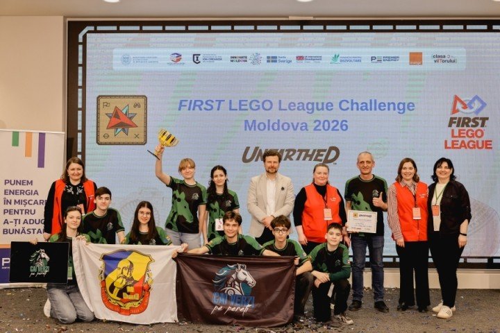 Церемония награждения на финале FIRST LEGO League в Кишинёве — команда-победитель с кубком на фоне баннера соревнований