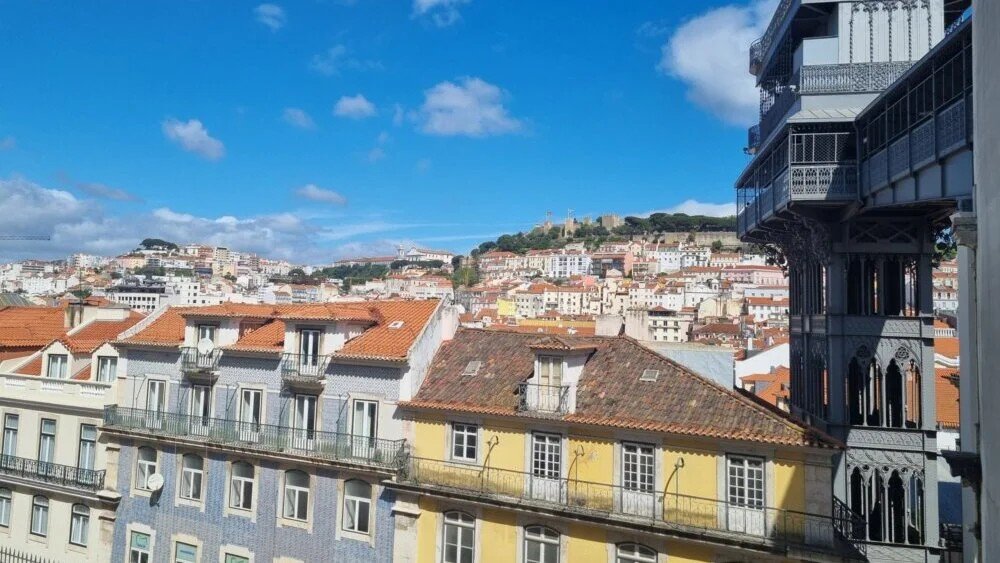 Lisbon cityscape with traditional buildings, orange rooftops, and Santa Justa elevator. Фото: Danas