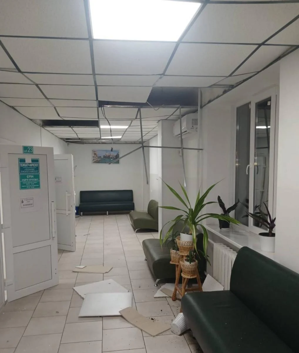 Damaged medical facility corridor with collapsed ceiling panels, debris on floor