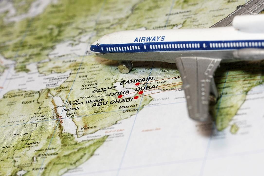 Модель самолёта над картой Ближнего Востока с отмеченными городами Дубай, Доха и Абу-Даби — направления отменённых рейсов