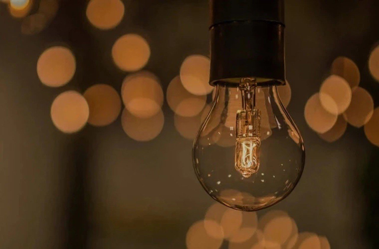 Лампа накаливания на размытом фоне огней — символ перебоев с электроснабжением в Молдове