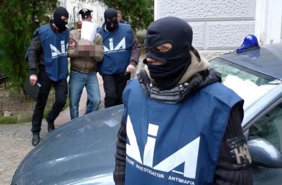 Сотрудники итальянского антимафиозного управления DIA в масках проводят задержание подозреваемого