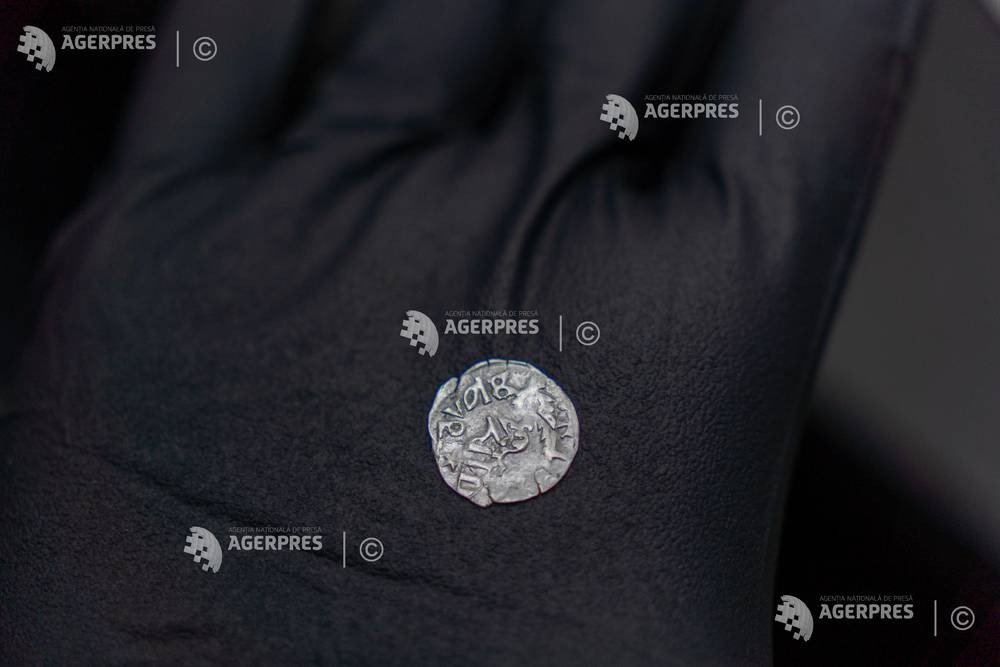 Серебряная монета эпохи Мирчи Старого на ладони в чёрной перчатке — оборотная сторона с надписями