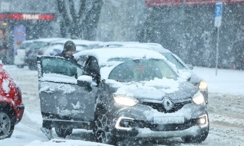 Водитель у автомобиля во время сильного снегопада в хорватском городе