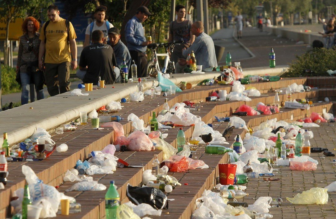 Мусор и пустые бутылки на городской набережной после массового гулянья