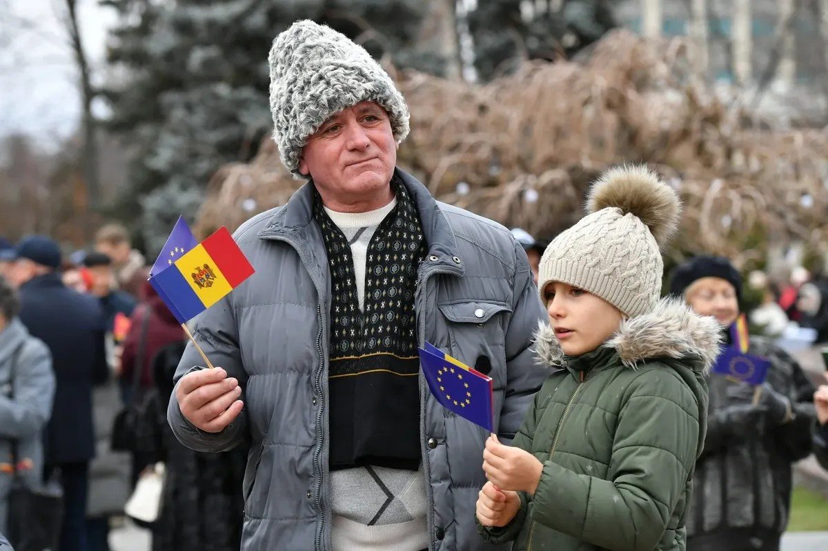 Мужчина и мальчик с флажками Молдовы и Евросоюза на публичном мероприятии — надежды на евроинтеграцию, объединяющие поколения