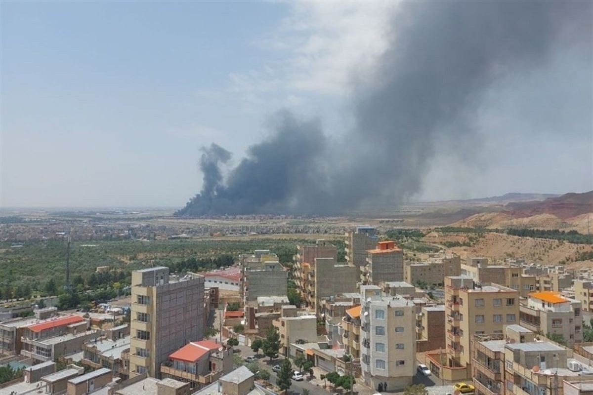Тёмный дым над иранским городом после авиаудара, на переднем плане жилые здания. Фото: OC Media