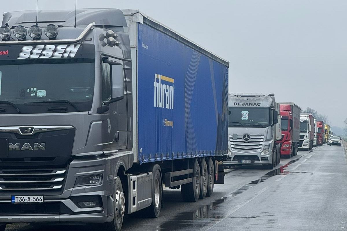 Колонна грузовиков с боснийскими номерами стоит в очереди на трассе в дождливую погоду