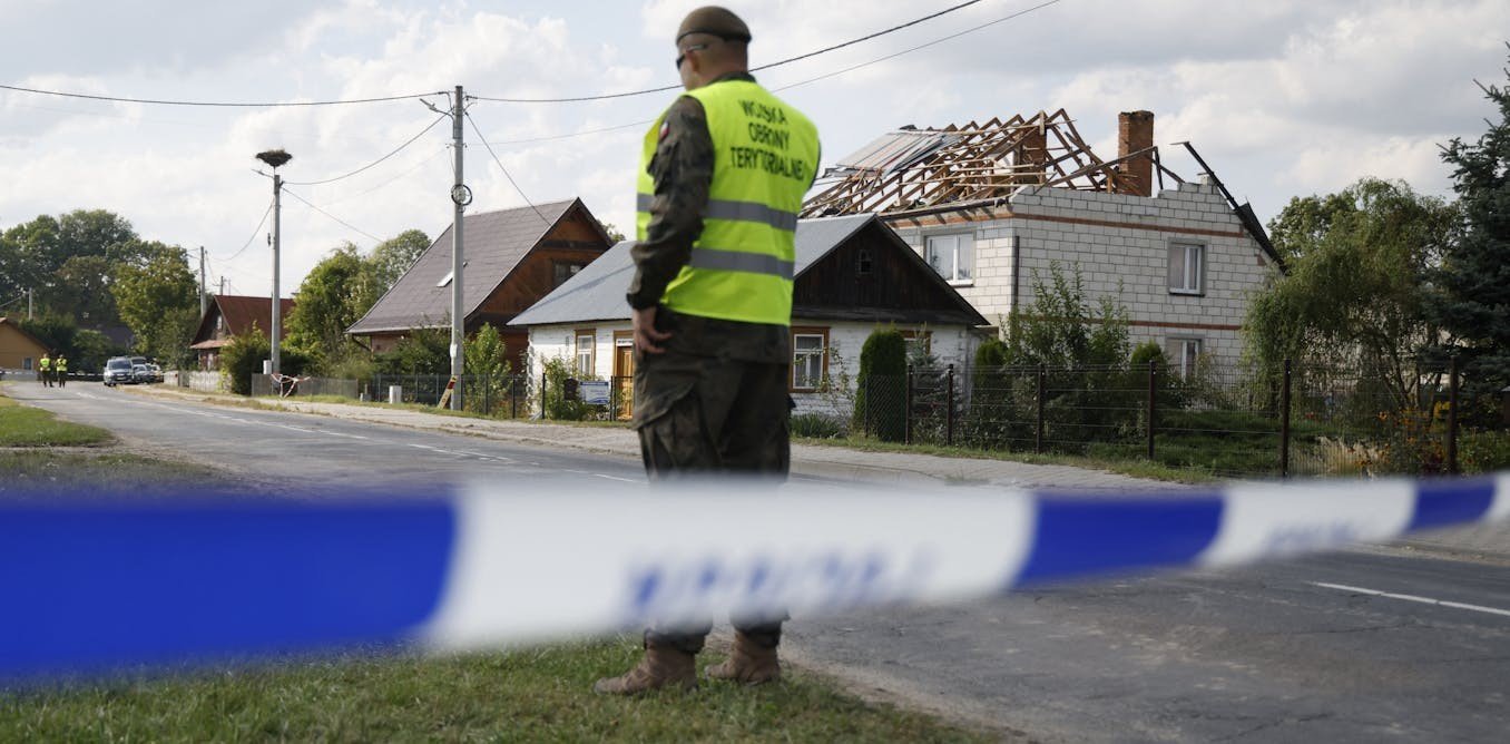 Военнослужащий территориальной обороны за полицейской лентой у дома, повреждённого в результате падения обломков — последствия нарушения воздушного пространства