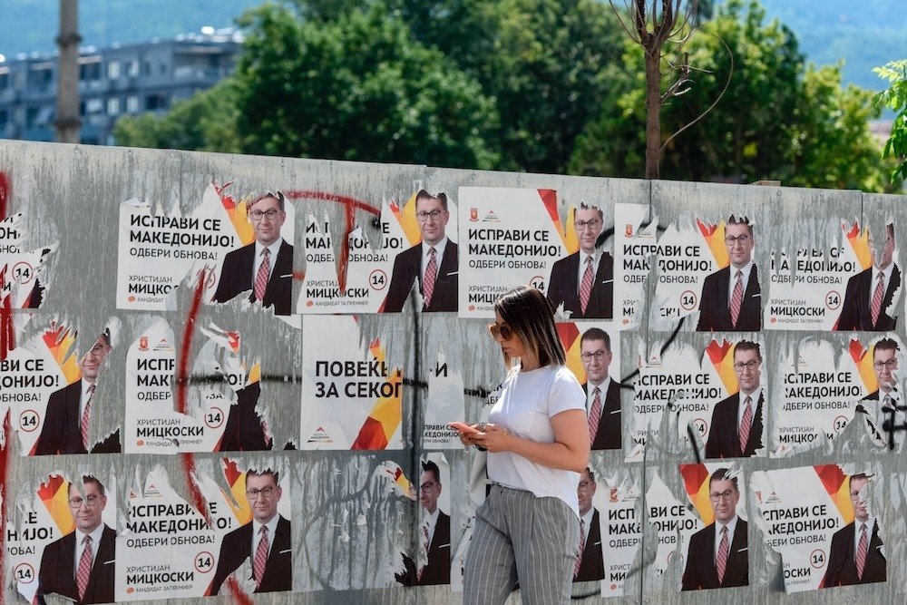 Девушка проходит мимо предвыборных плакатов Христиана Мицкоски (ВМРО-ДПМНЕ) на улице в Северной Македонии