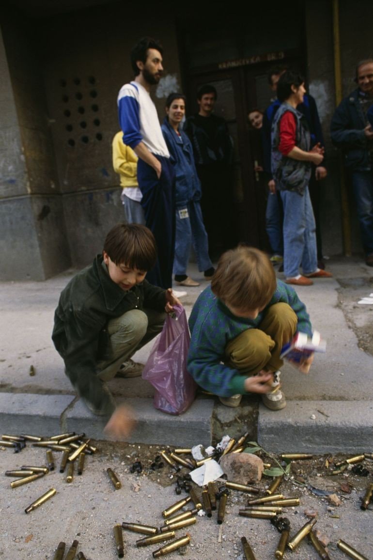 Дети собирают гильзы на улице осаждённого Сараево — обстрелы были частью повседневной жизни горожан