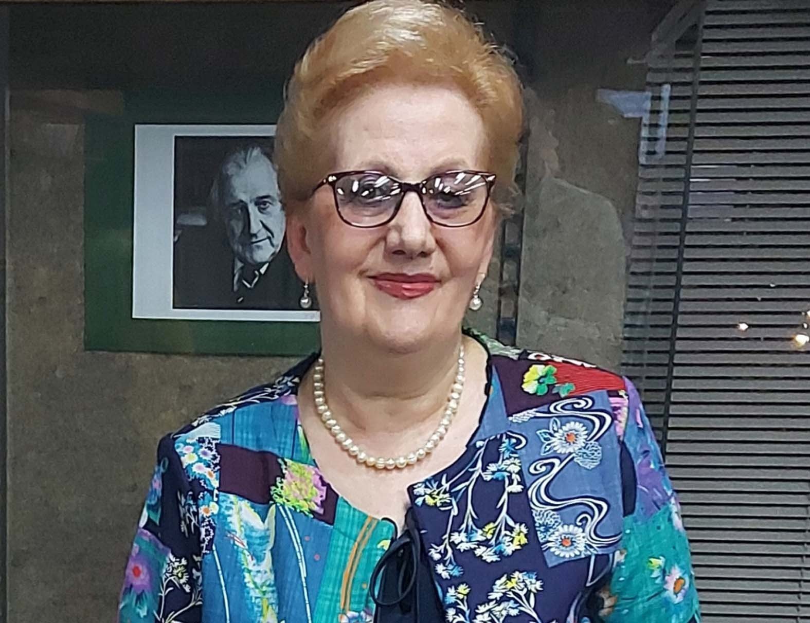 Woman in colorful floral blouse with pearl necklace and glasses. Фото: Danas