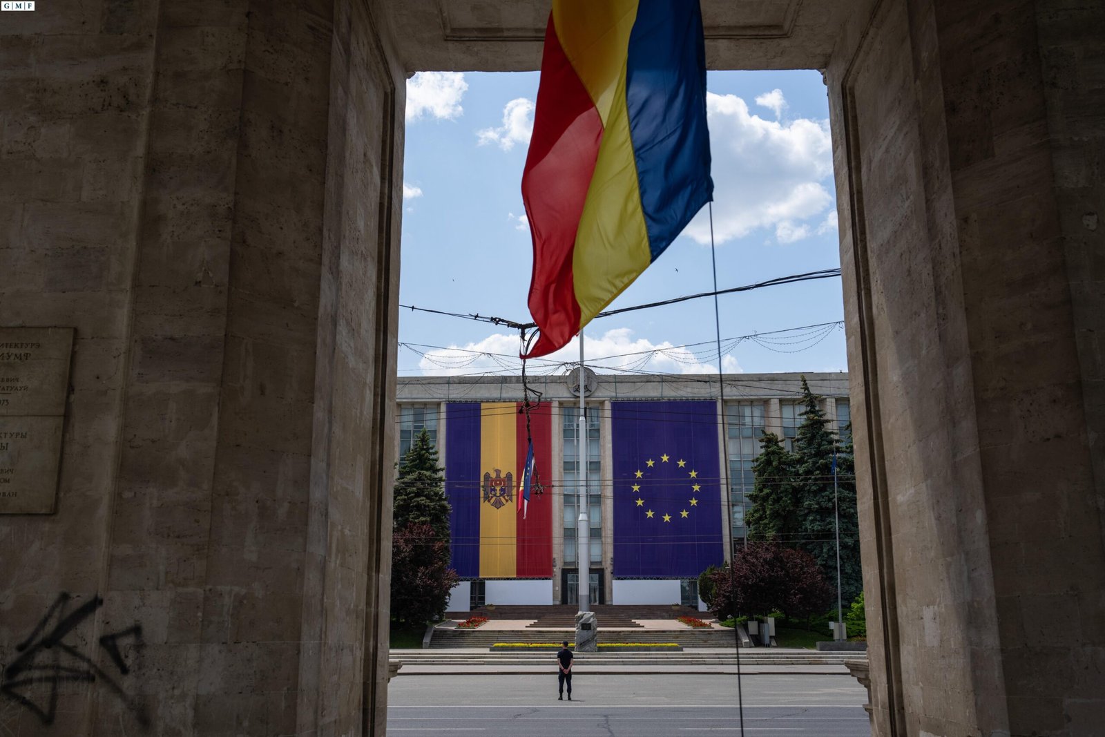 Chisinau government building viewed through Triumphal Arch with large Moldova and EU flags displayed on facade. Фото: German Marshall Fund