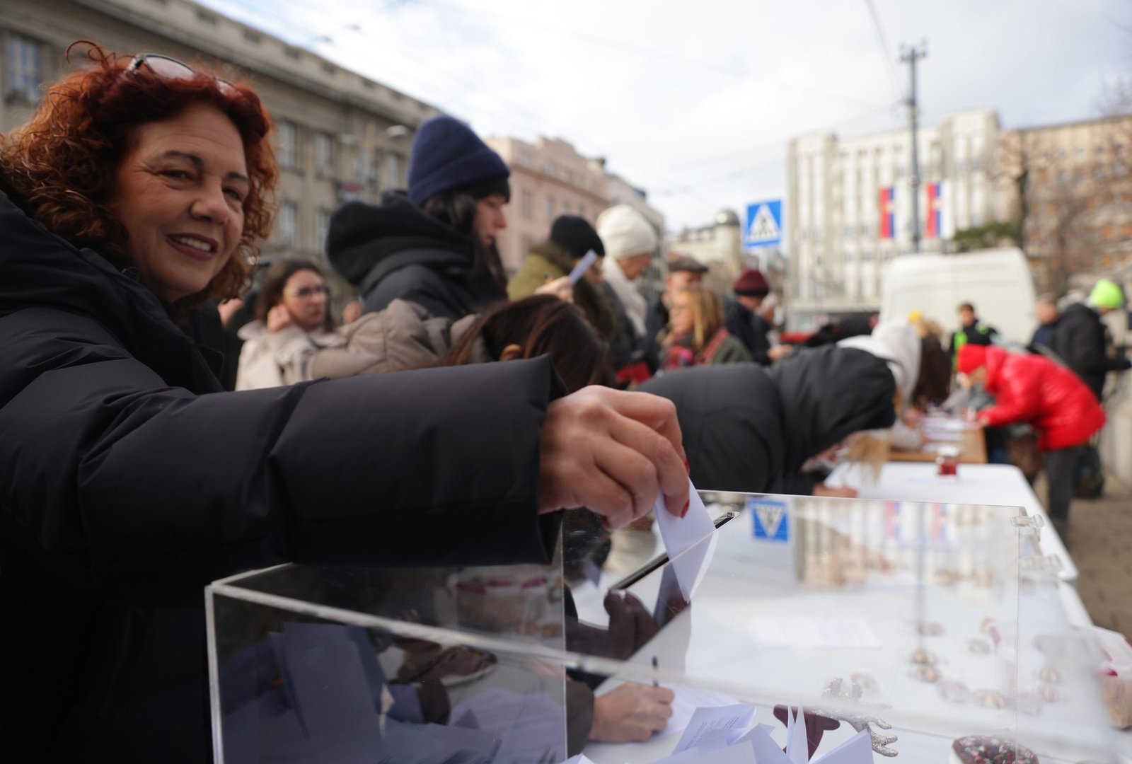 Женщина опускает символический бюллетень в прозрачную урну на уличной акции. Фото: EUalive