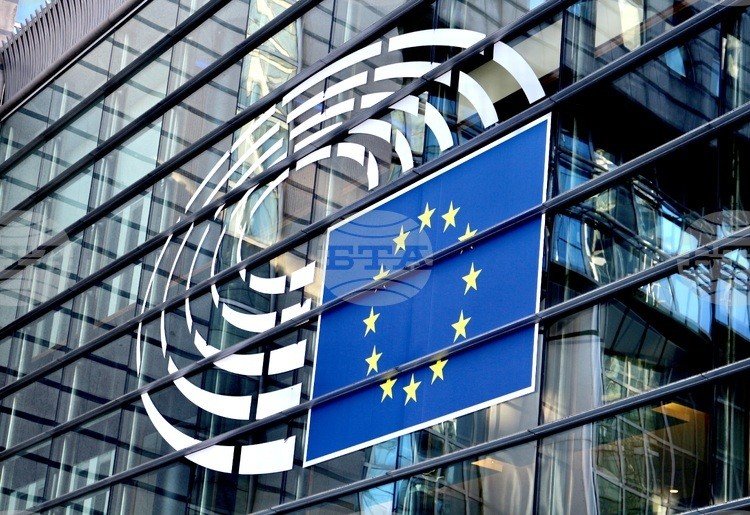 Здание Европейского парламента в Брюсселе с логотипом и флагом ЕС на фасаде