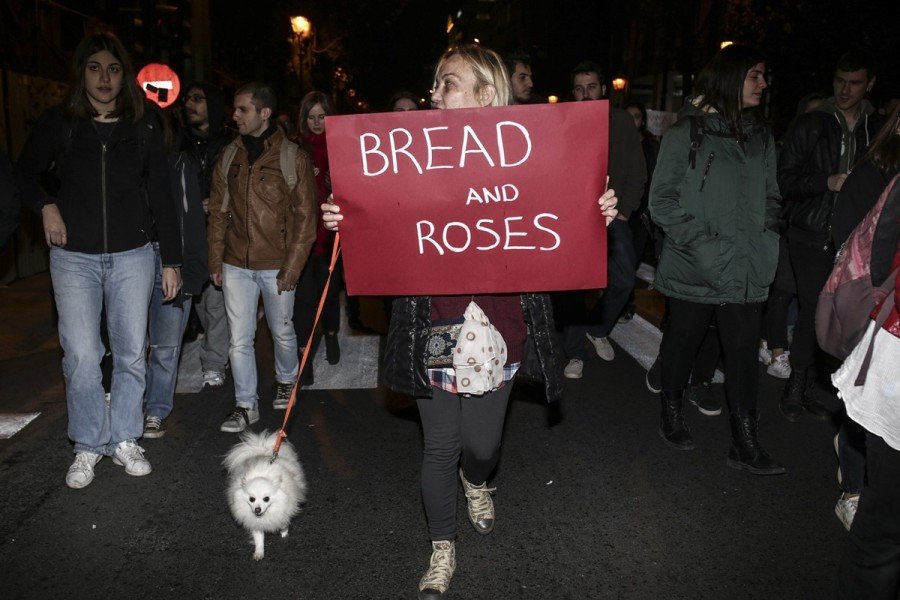 Женщина с плакатом «Bread and Roses» на ночном марше в Афинах