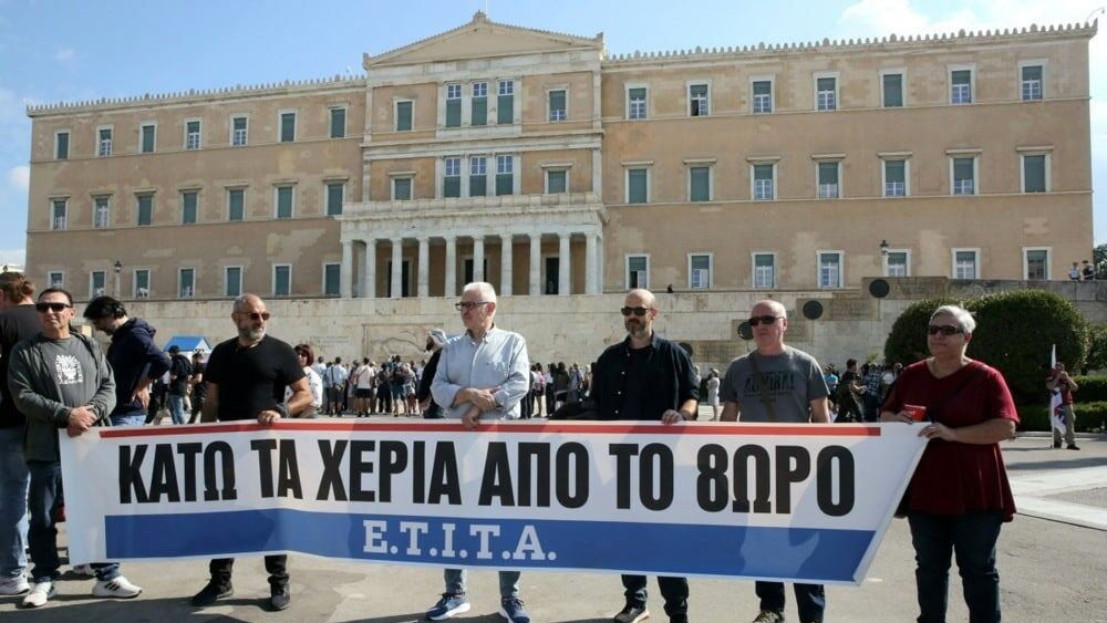 Протестующие с баннером «Руки прочь от 8-часового дня» у здания парламента Греции