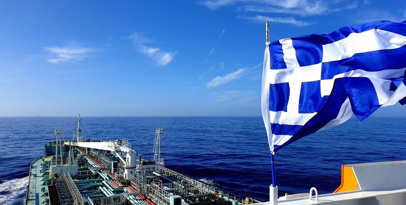 Греческий флаг на палубе танкера в открытом море под ярко-голубым небом