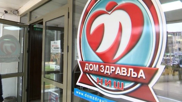 Вход в здание Дома здравља в Нише с логотипом учреждения на стеклянной двери