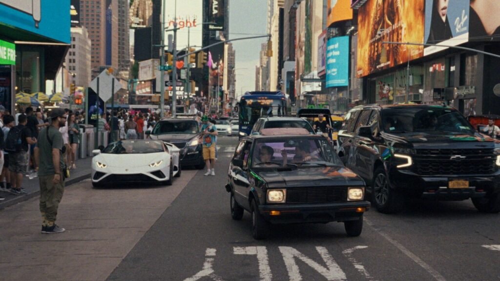 Сербский «Юго» доехал до Копенгагена: премьера на CPH:DOX Автомобиль Zastava Yugo едет по Таймс-сквер в Нью-Йорке рядом с Lamborghini — кадр из документального фильма «Yugo Goes to America»