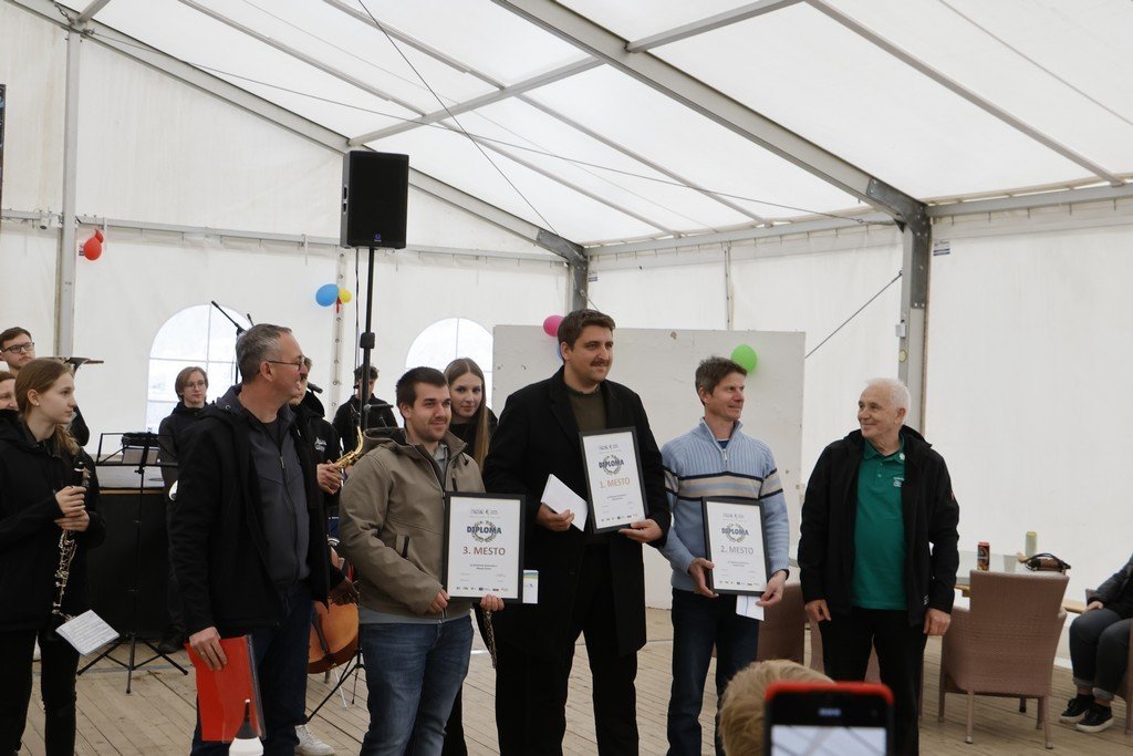 Чемпион Словении снова победил в натирании хрена Победители соревнования по натиранию хрена на сцене с дипломами в руках на 20-м Пасхальном ярмарке в Сновике