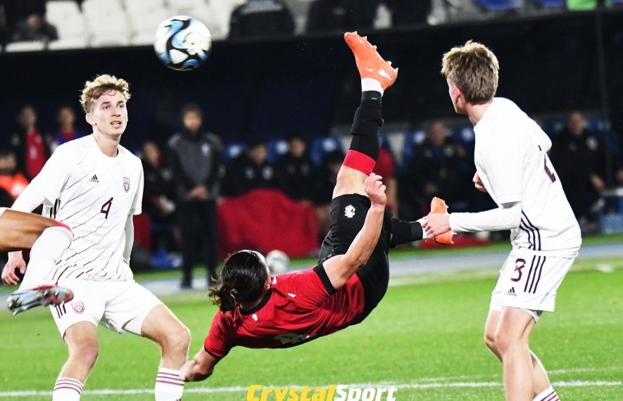 Игрок сборной Грузии U21 наносит удар через себя в окружении двух латвийских защитников во время квалификационного матча Евро U21 в Кутаиси