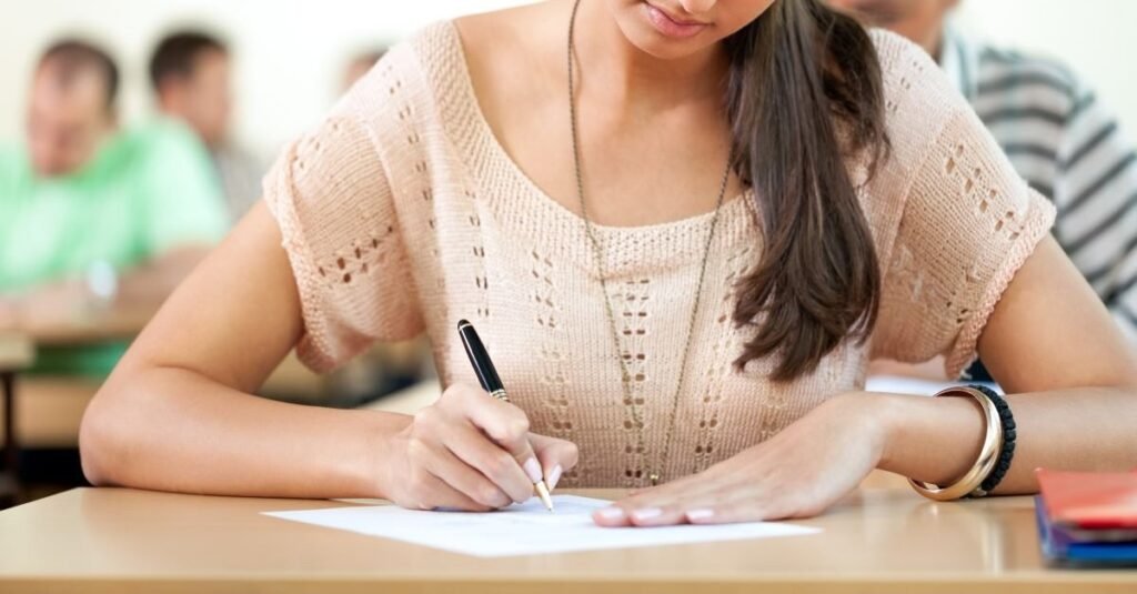 Ученица пишет экзаменационную работу за партой в классе