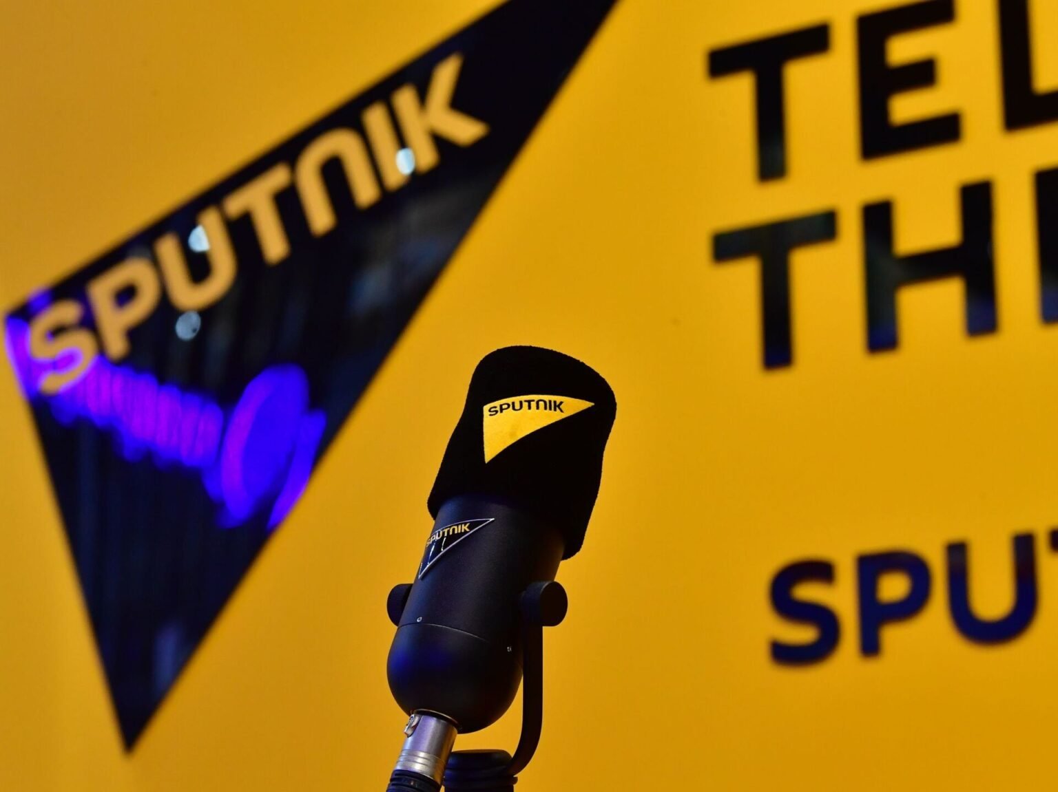 Микрофон с логотипом Sputnik на фоне брендированной стены российского государственного медиахолдинга