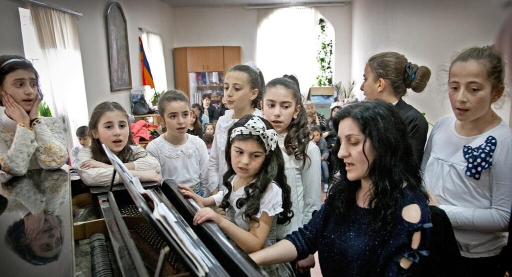 Один врач на весь Джавахети: тихая драма армян Грузии Армянские дети поют у пианино с учительницей музыки в школе искусств региона Самцхе-Джавахети, на стене — армянский флаг
