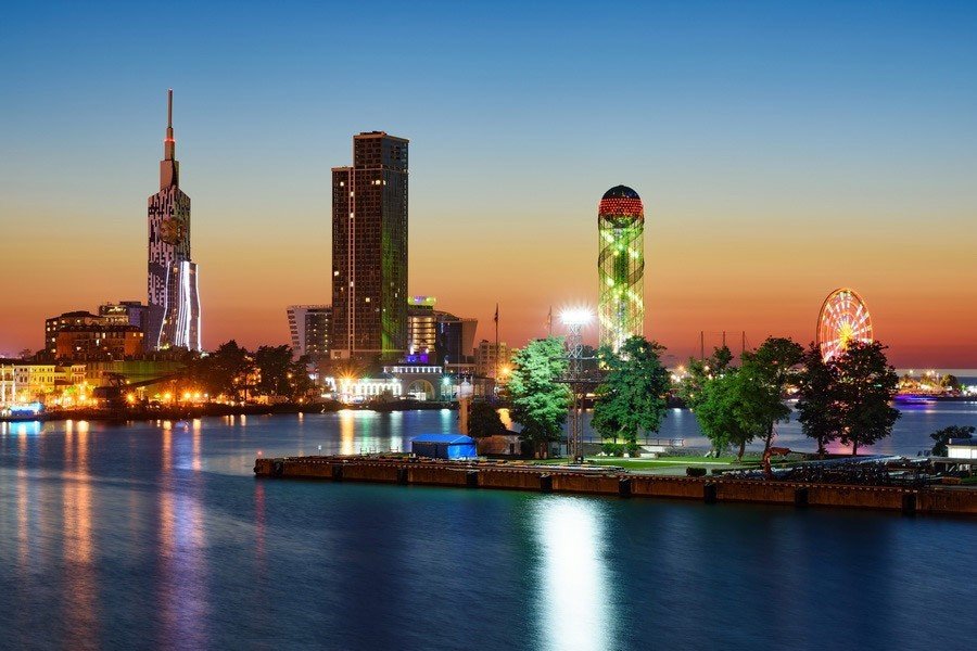 Панорама набережной Батуми на закате с подсвеченными небоскрёбами и колесом обозрения