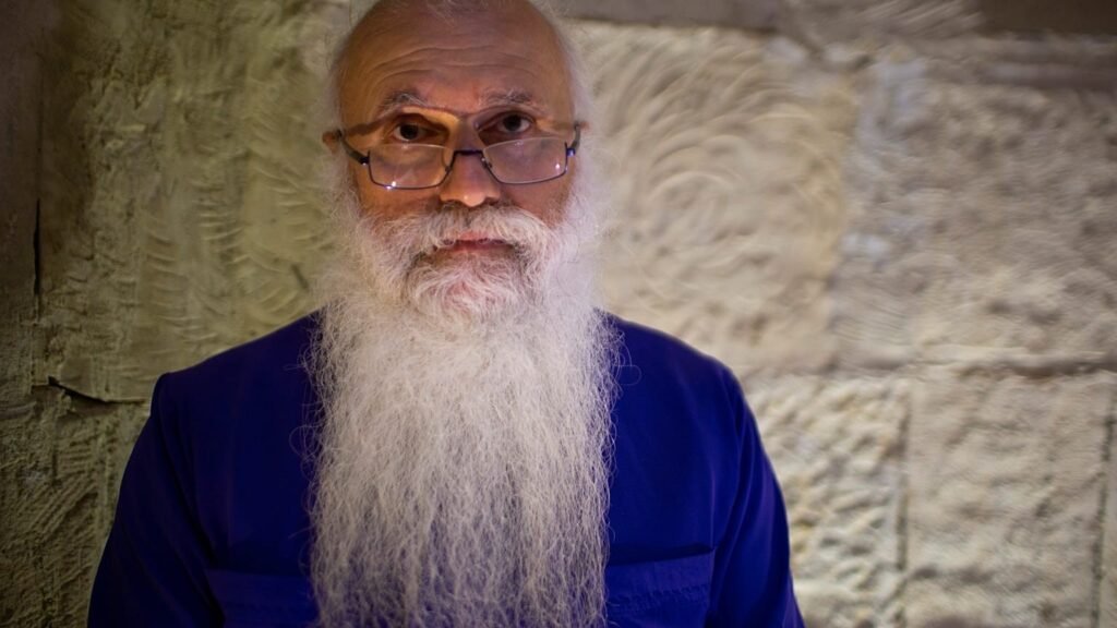 Портрет епископа Малхаза Сонгулашвили, митрополита-архиепископа Евангелическо-баптистской церкви Грузии, в фиолетовом облачении на фоне каменной стены