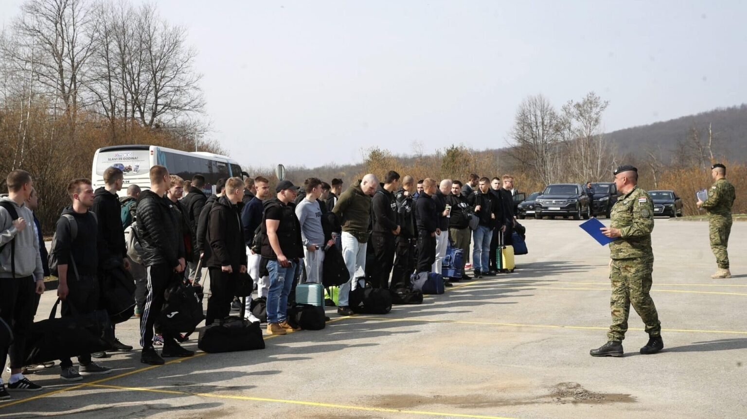 Молодые хорватские призывники выстроились с сумками на плацу военной базы в ожидании инструктажа