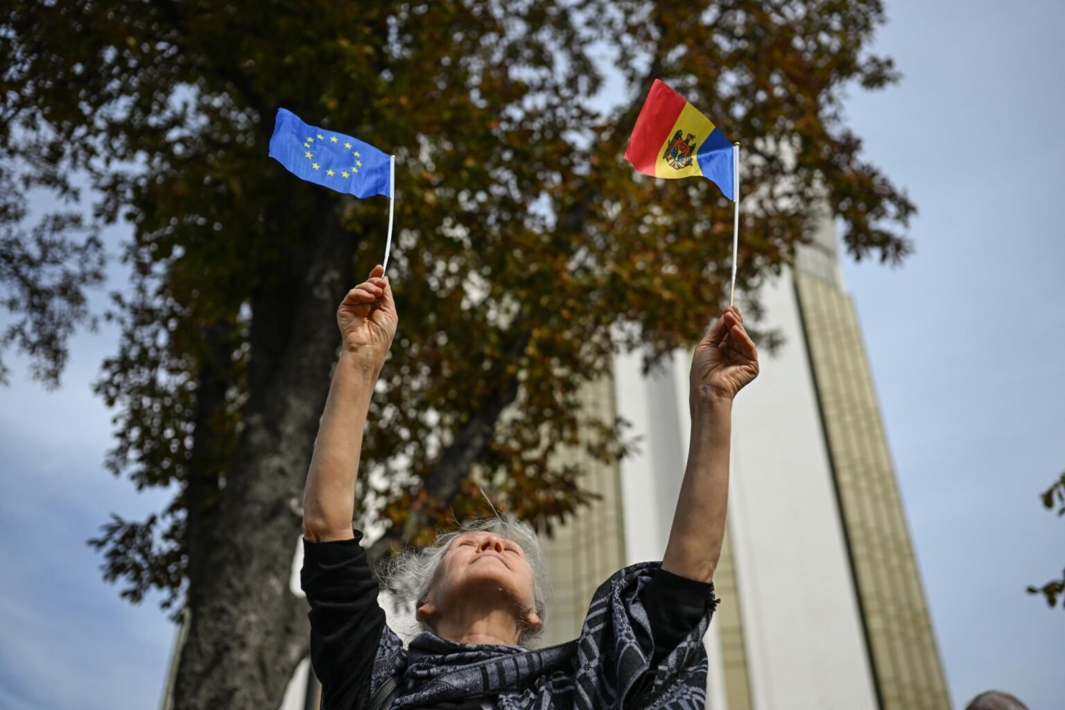 Woman holding EU and Moldovan flags raised above her head, symbolic image of Moldova's EU aspirations. Фото: European Council on Foreign Relations