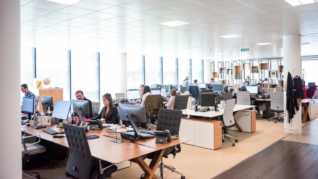 Сотрудники работают за компьютерами в современном офисе открытого типа