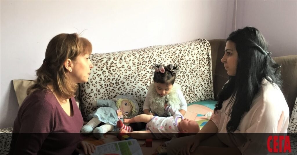 Патронажная медсестра во время домашнего визита к молодой маме с детьми