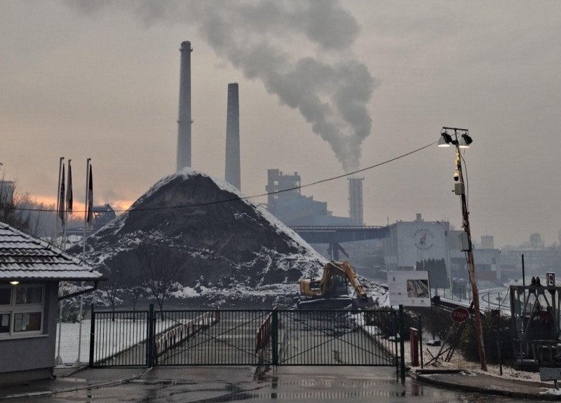 Зимний вечер на золоотвале «Энергетики» в Крагуеваце: огромная гора золы, покрытая снегом, дымящие трубы ТЭЦ и экскаватор у подножия отвала