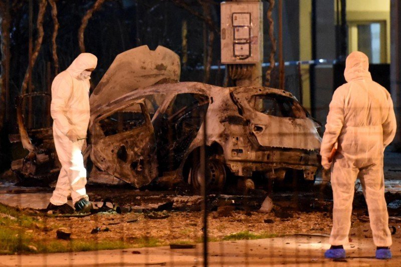 Криминалисты в белых защитных костюмах у обгоревшего автомобиля ночью в Подгорице