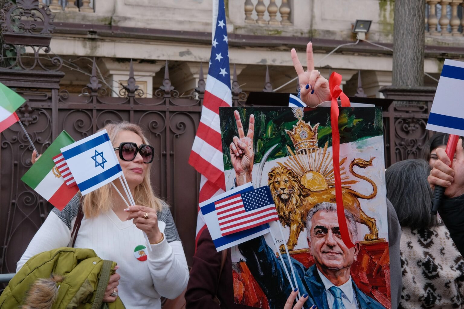 Участники протеста иранской диаспоры в Бухаресте с флагами Израиля, США и дореволюционного Ирана, плакат с изображением Резы Пехлеви. Фото: HotNews.ro