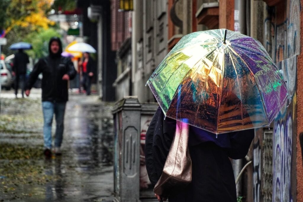 Ливни, снег и гололёд: Сербия готовится к трёхдневной непогоде Прохожие с зонтами идут по мокрой улице во время ливня