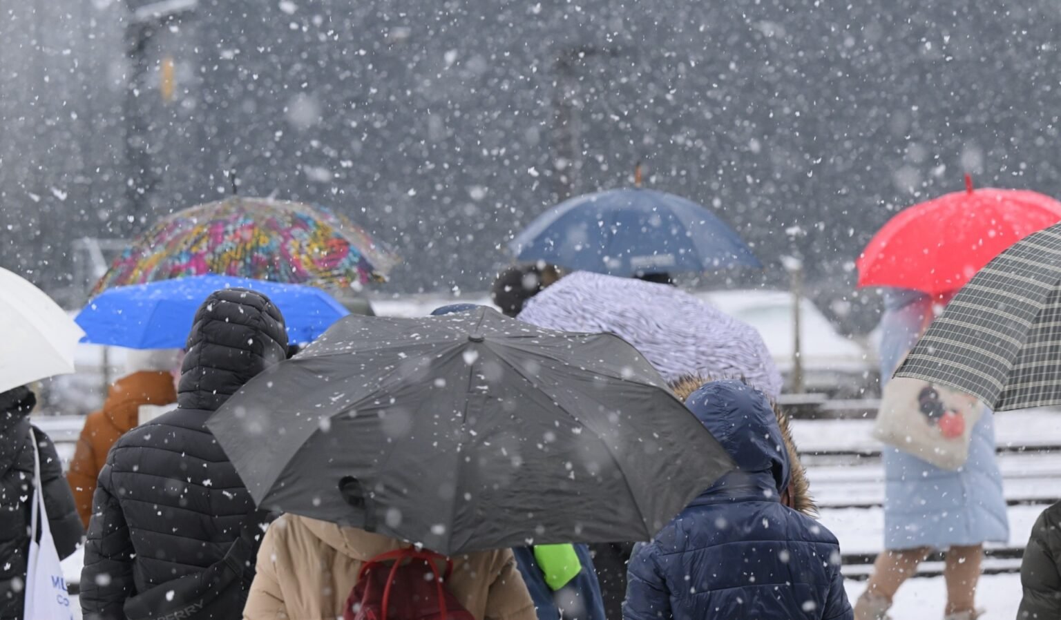 Прохожие с разноцветными зонтами идут сквозь густой снегопад в Словении