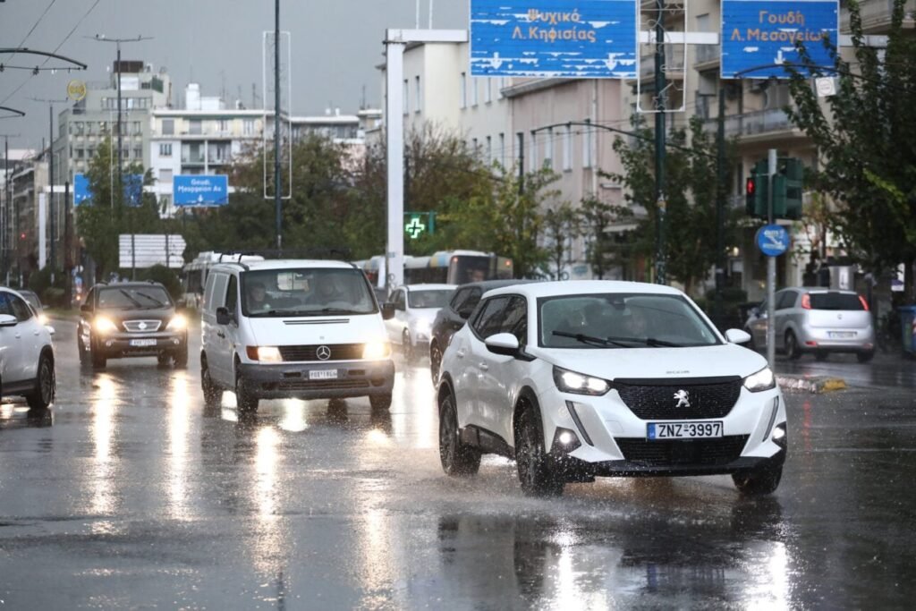 Автомобили едут по залитым дождём улицам Афин во время шторма «Дебора», мокрые дороги и пасмурное небо над проспектом Кифисиас