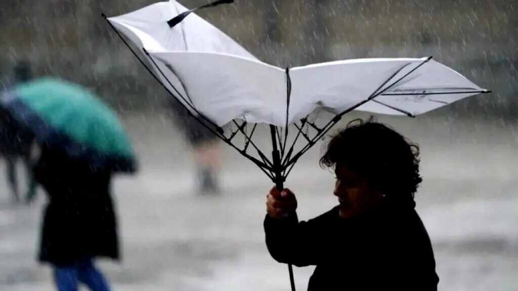 Женщина с вывернутым зонтом под проливным дождём и сильным ветром