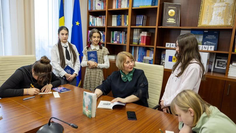 Школьницы Кишинёва на встрече с представителем администрации в кабинете на фоне флагов Молдовы и Евросоюза