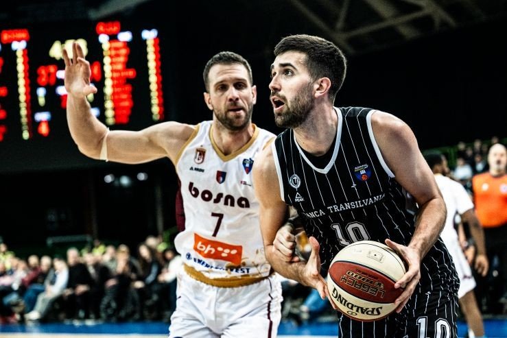 Игрок У-БТ Клуж в чёрной форме идёт в атаку с мячом мимо защитника «Босны» №7