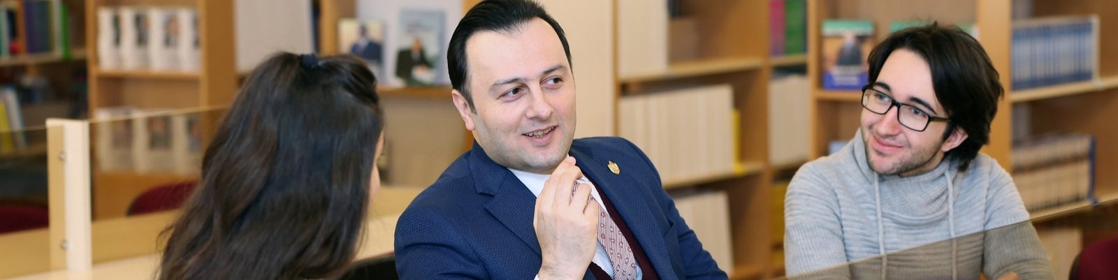 Преподаватель и студенты в библиотеке Бакинской высшей школы нефти обсуждают учебный процесс