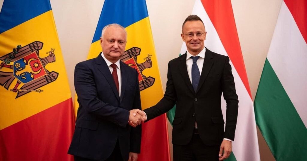 Игорь Додон и Петер Сийярто пожимают руки на фоне молдавского и венгерского флагов