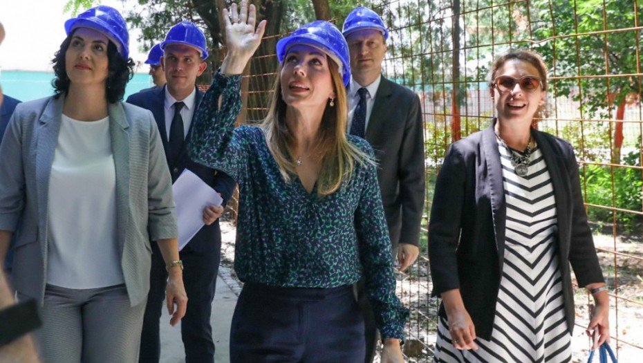 Делегация чиновников в строительных касках осматривает площадку энергетической реновации жилого здания